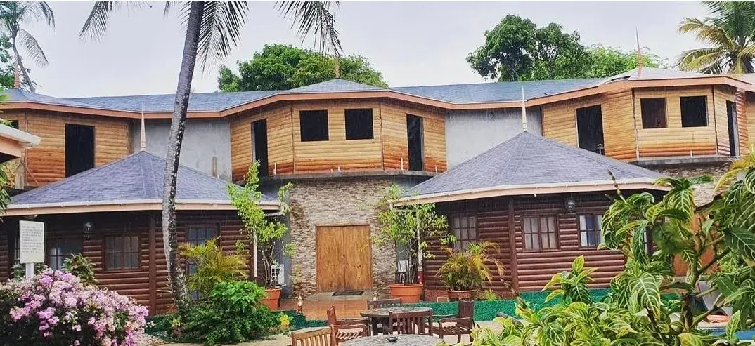 Wide view of the timber lodge buildings framed by palms