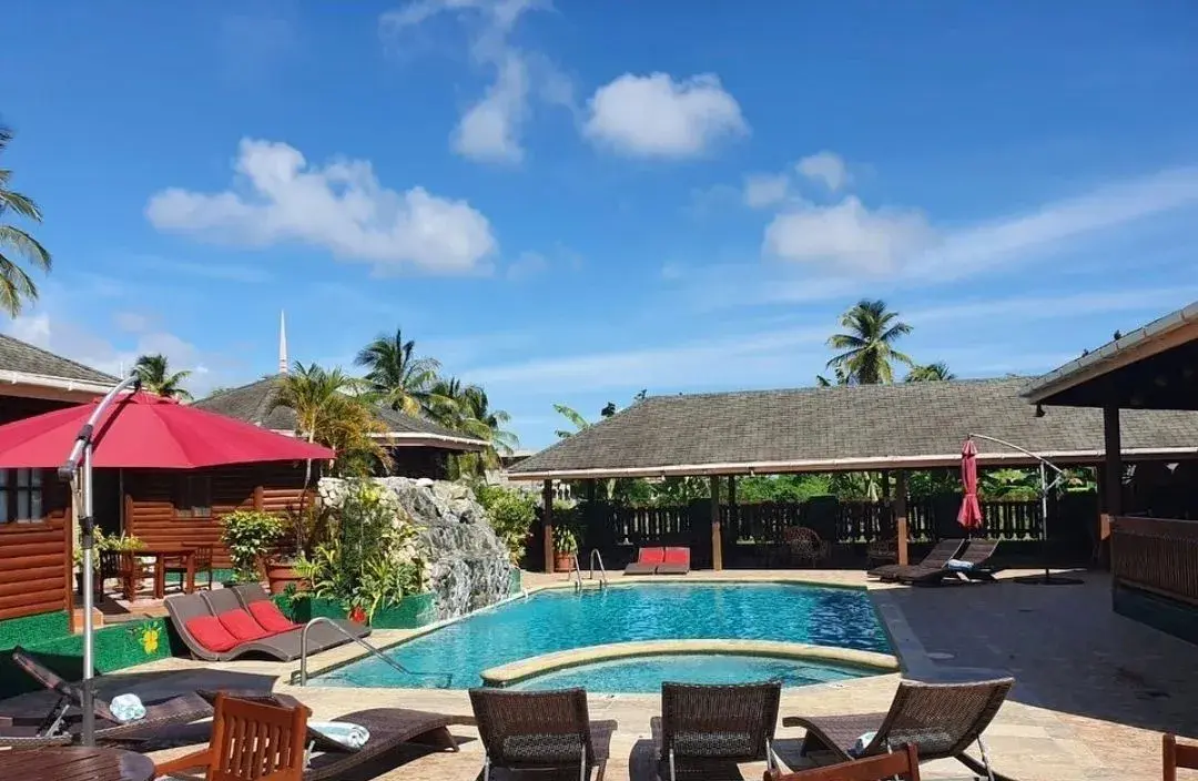 Pool and red parasols under a bright blue Tobago sky