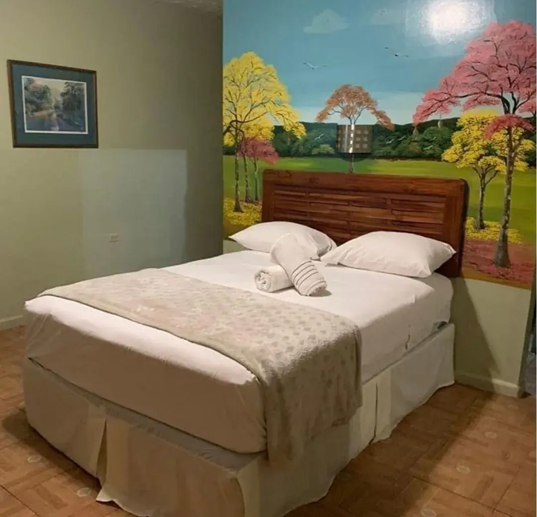 Guest room with a hand-painted garden mural behind the bed