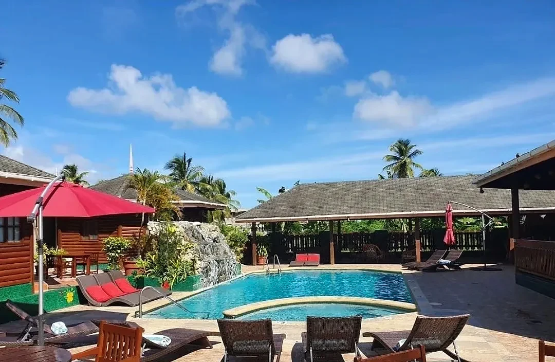 Pool and red parasols under a bright blue Tobago sky
