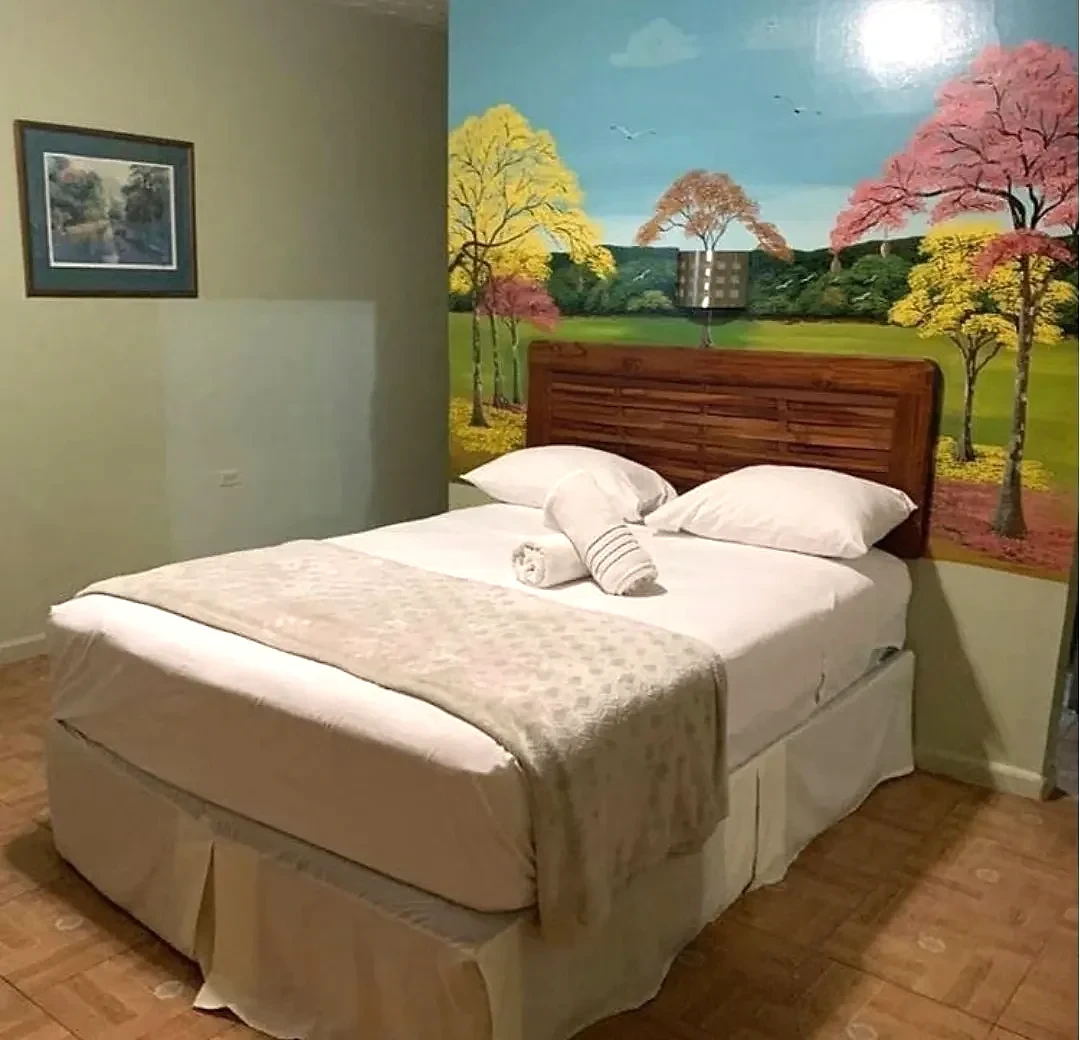 Guest room with a hand-painted garden mural behind the bed